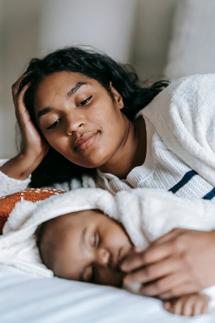 Young African American mother embracing her sleeping infant