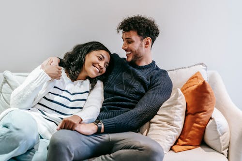 Smiling multiracial couple hugging on couch