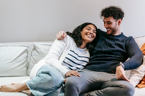 Free Happy barefoot African American girlfriend with closed eyes and ethnic boyfriend hugging on sofa in cozy living room at home Stock Photo