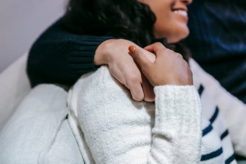 Crop diverse couple hugging on couch