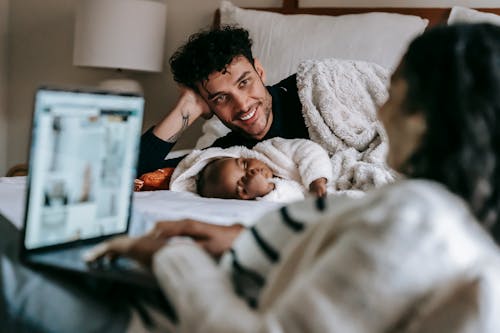 Free Multiethnic family with laptop in bedroom with infant baby Stock Photo