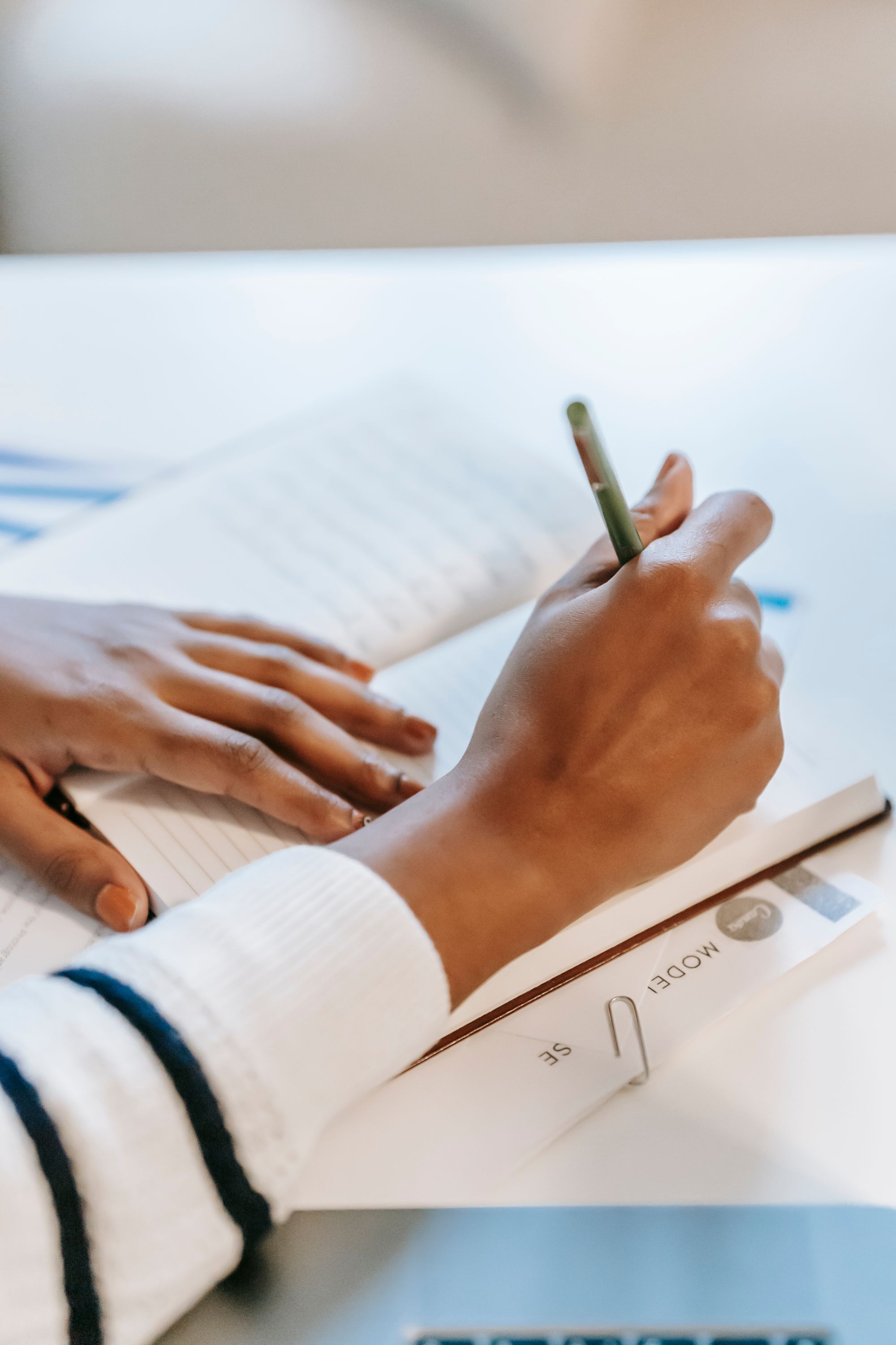 A Black woman writing carefully by hand at a desk
