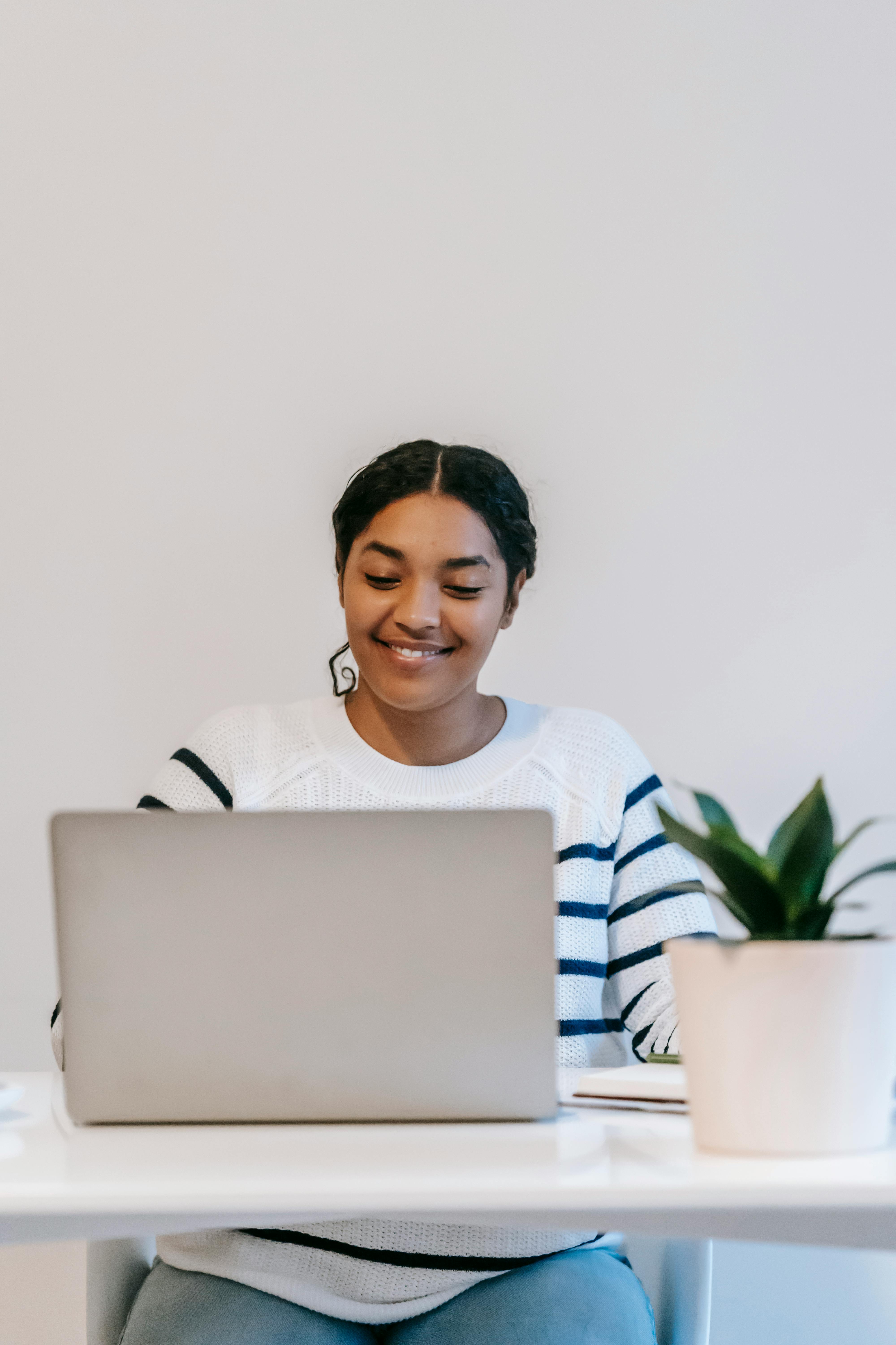 ethnic lady working remotely on netbook at table in room