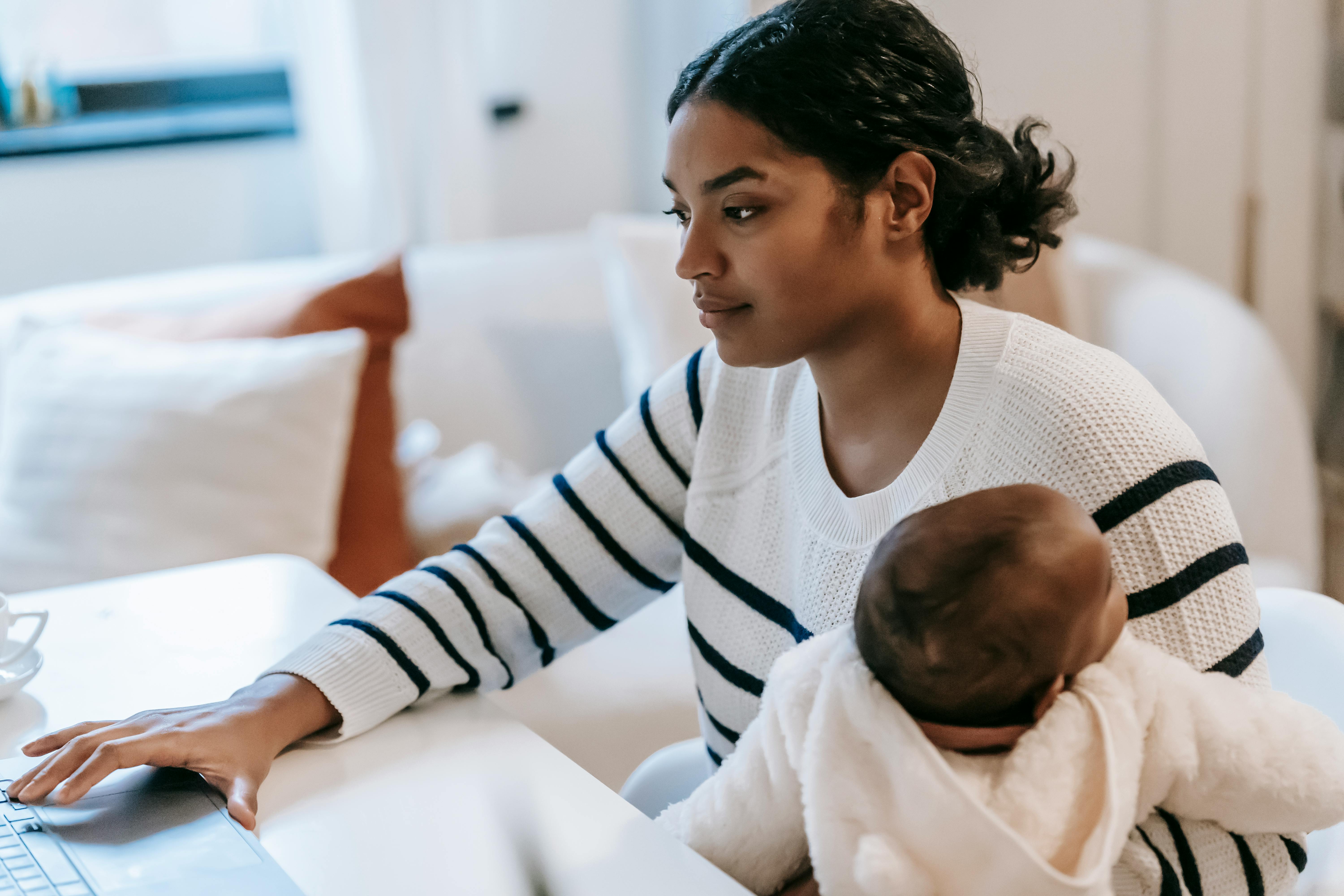 mother carrying her baby while working from home