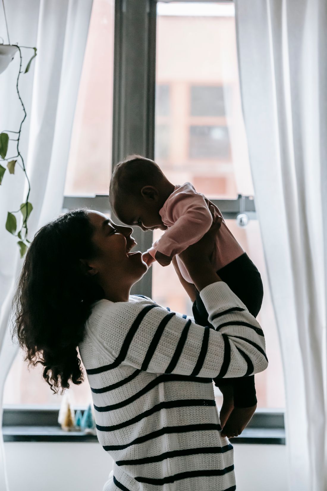 Mãe carregando o bebê no colo, em casa, com roupas do dia a dia