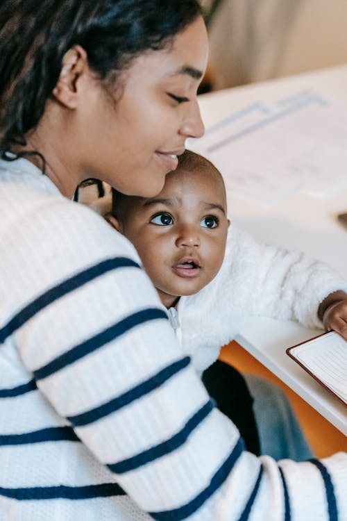Free Indian female with baby near notepad at table Stock Photo