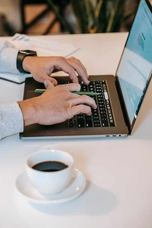 Student sitting at table with cup of coffee and browsing laptop