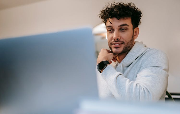 Smiling Distance Employee In Smart Watch Against Laptop At Home