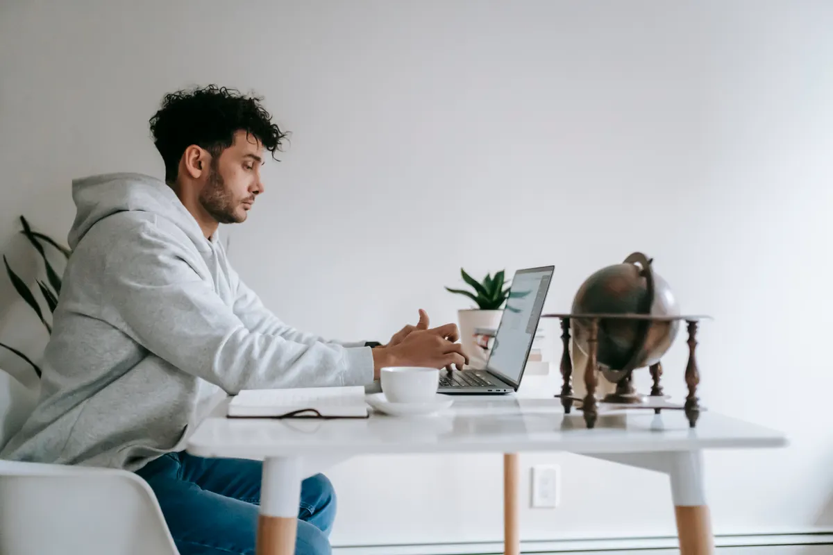 Pekerja remote duduk di rumah membuka laptop untuk mengerjakan proyek freelance side hustle tambahan
