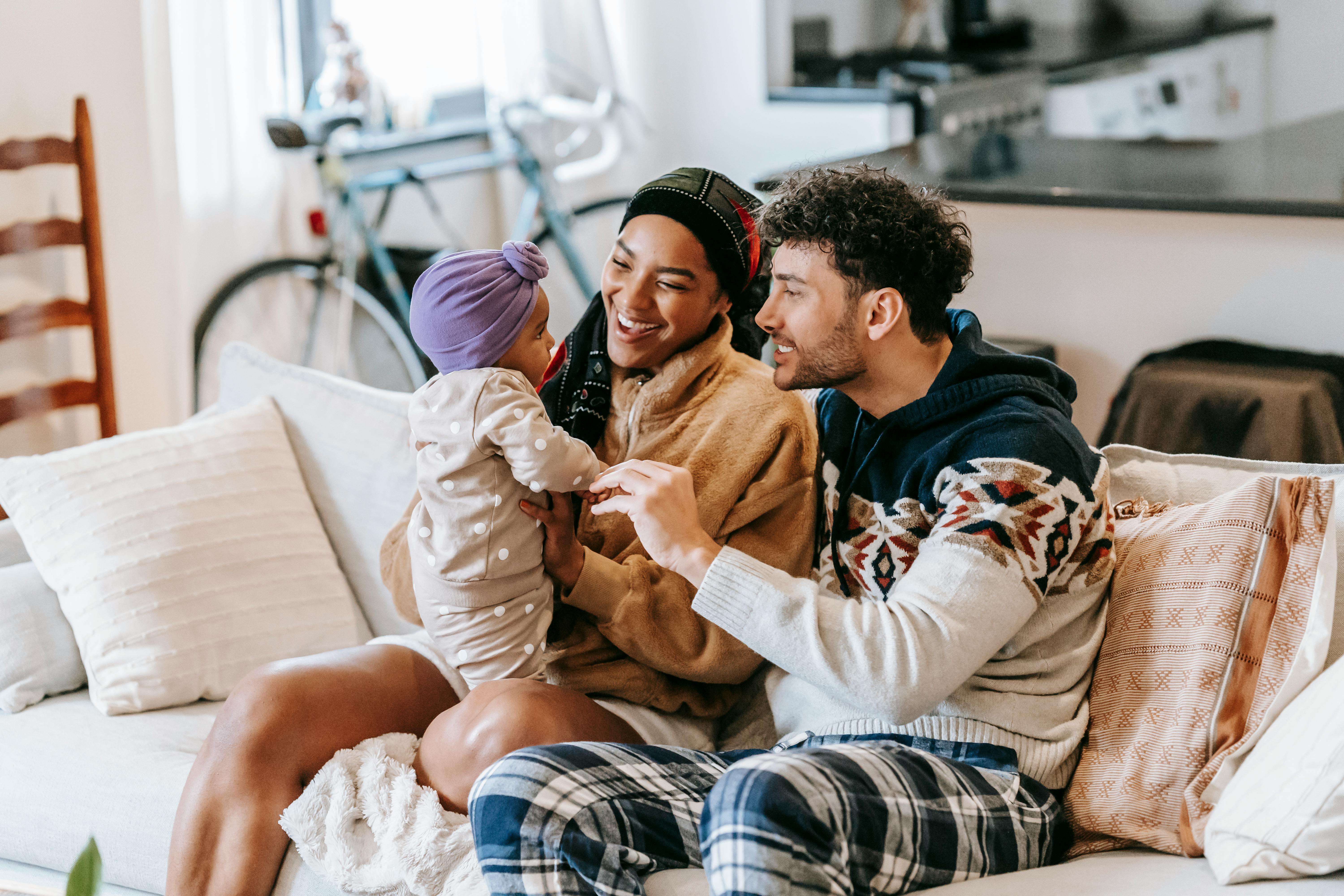 happy diverse family talking to little girl on sofa indoors