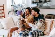 Happy diverse family talking to little girl on sofa indoors