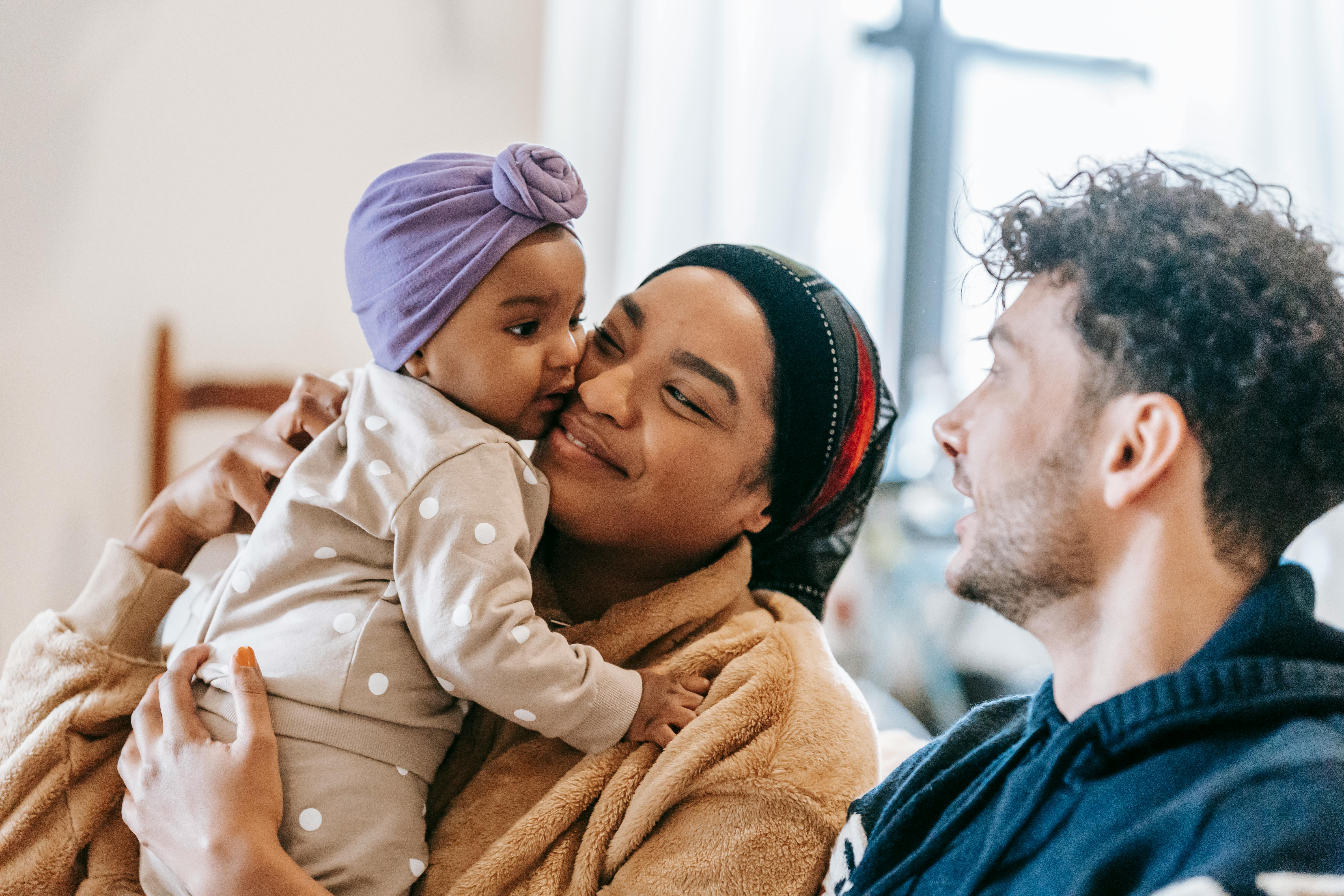 dad near black mother embracing little daughter at home