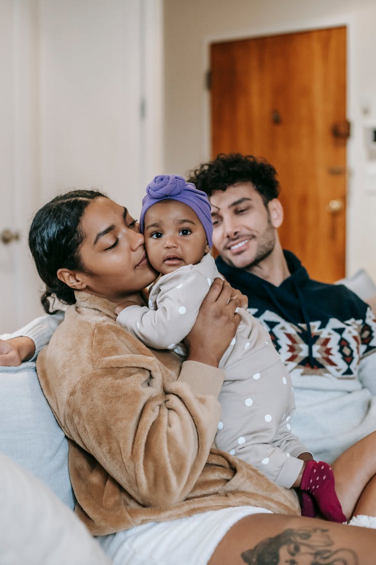 Diverse Family With Adorable Toddler Girl On Sofa At Home