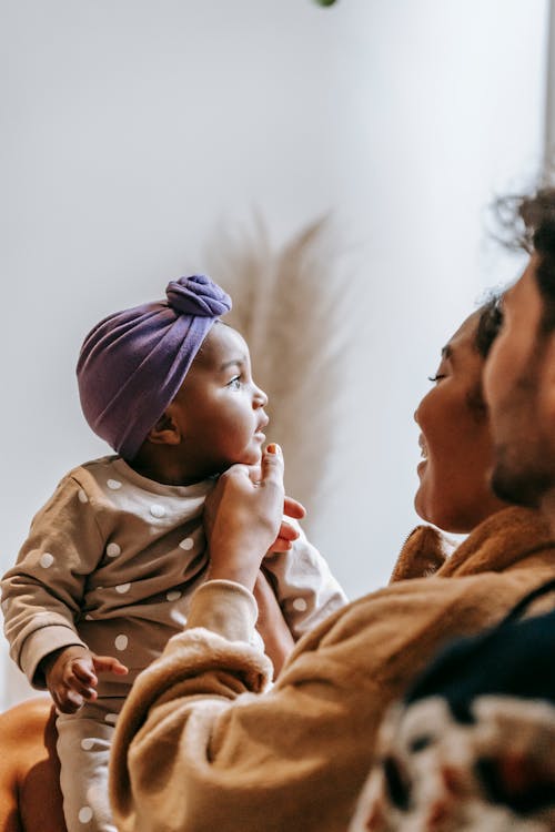 Free Crop anonymous bearded father near smiling black mom and contemplative little child in house room Stock Photo