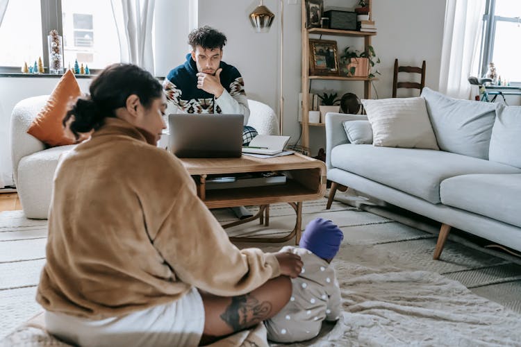 Diverse Family With Unrecognizable Baby In Room With Laptop