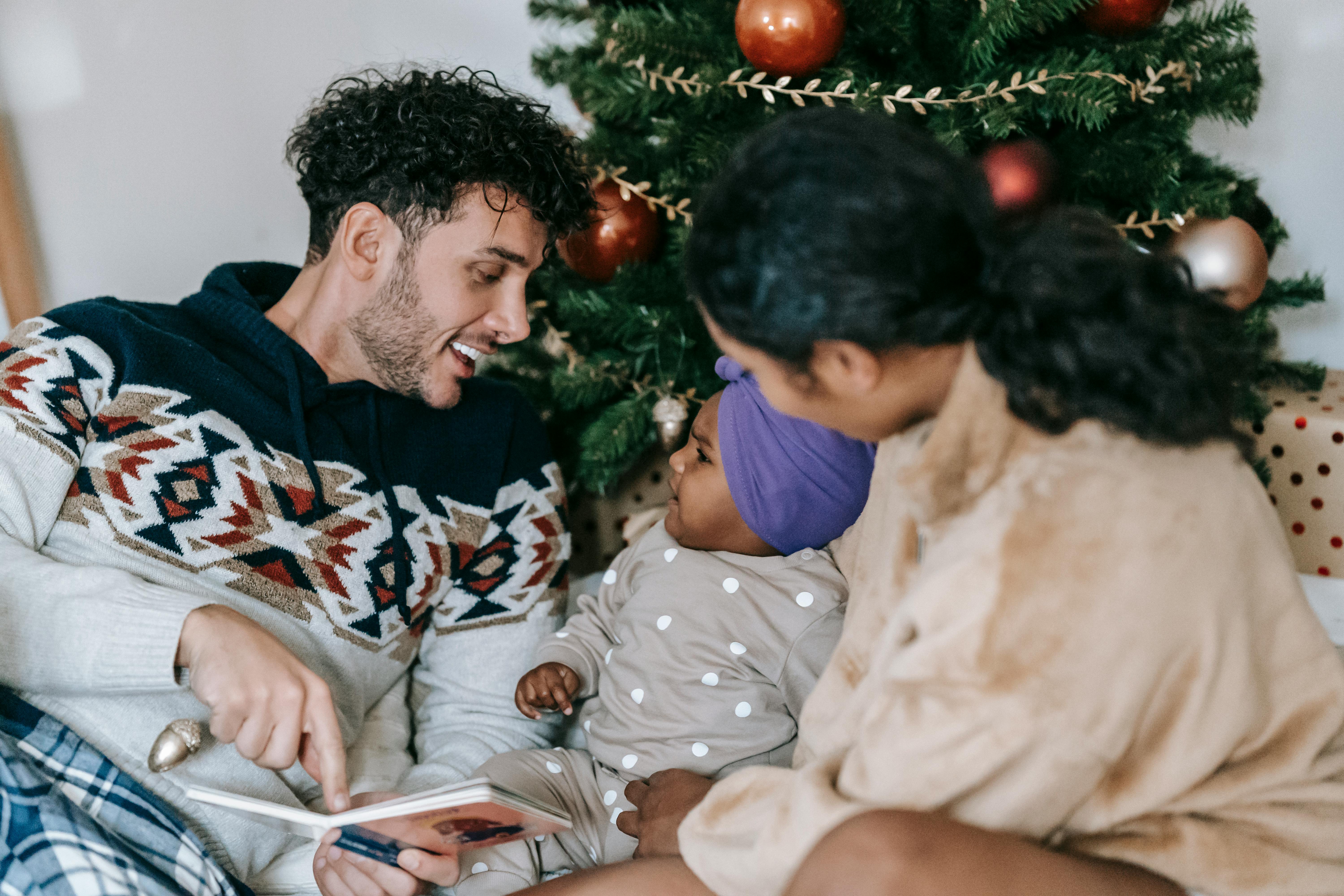 happy diverse family with little daughter with book ear christmas tree