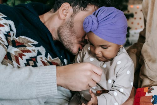 Bearded father kissing and playing with black baby
