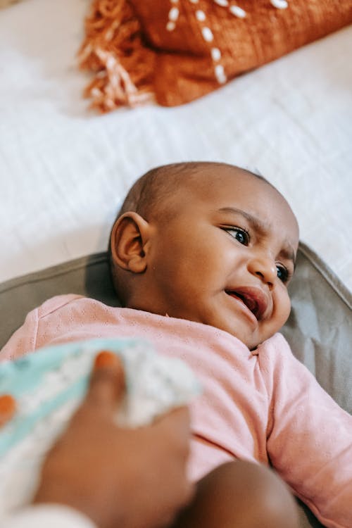 Free From above of crop anonymous female wearing soft diaper on small cute curious African American infant Stock Photo