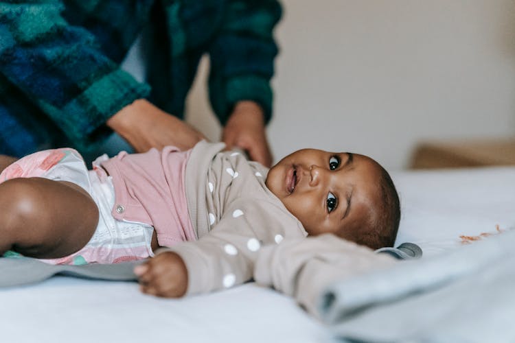 Cute Little Black Baby Lying On Bed