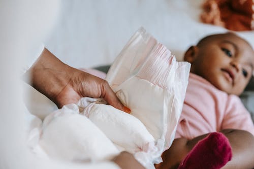 Free Black mother changing diaper for baby Stock Photo