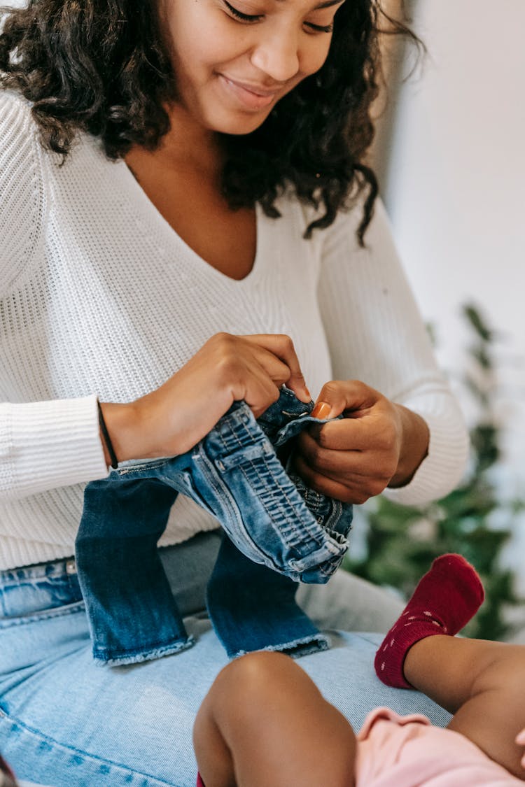 Positive Ethnic Woman Dressing Little Baby