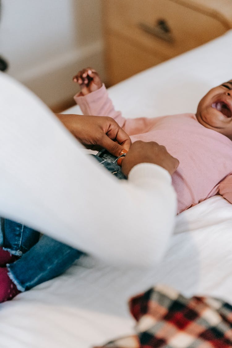 Mother Dressing Crying Baby At Home