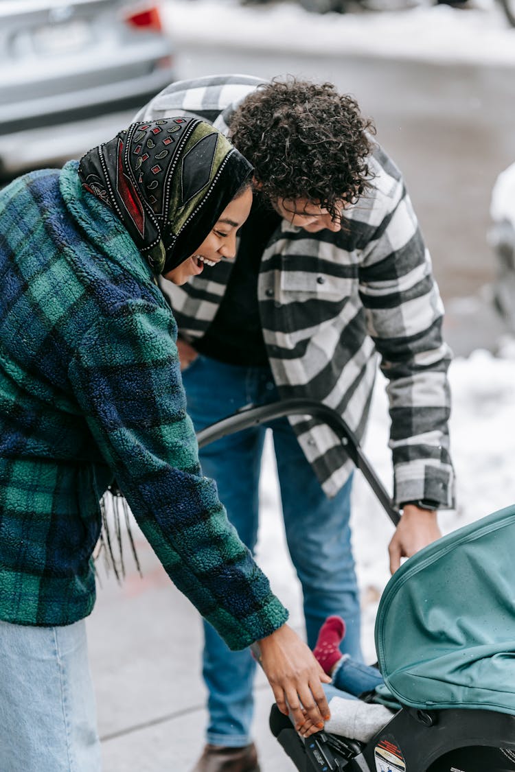 Ethnic Couple Walking With Stroller On Street