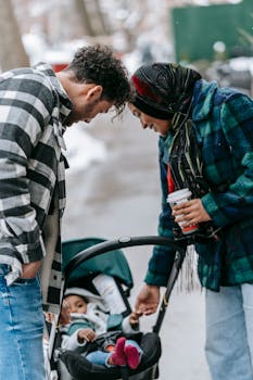 Smiling parents bond with baby in stroller during winter urban walk.