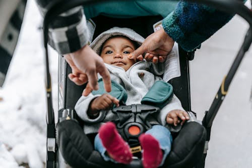 Free Calm baby lying in stroller while walking on street with parents Stock Photo