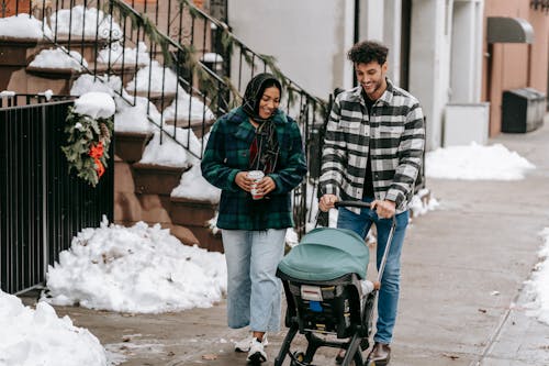 Positive ethnic couple having stroll with baby in stroller