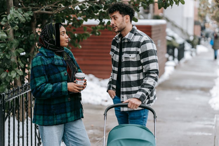 Young Ethnic Couple Talking On Sidewalk Standing With Stroller