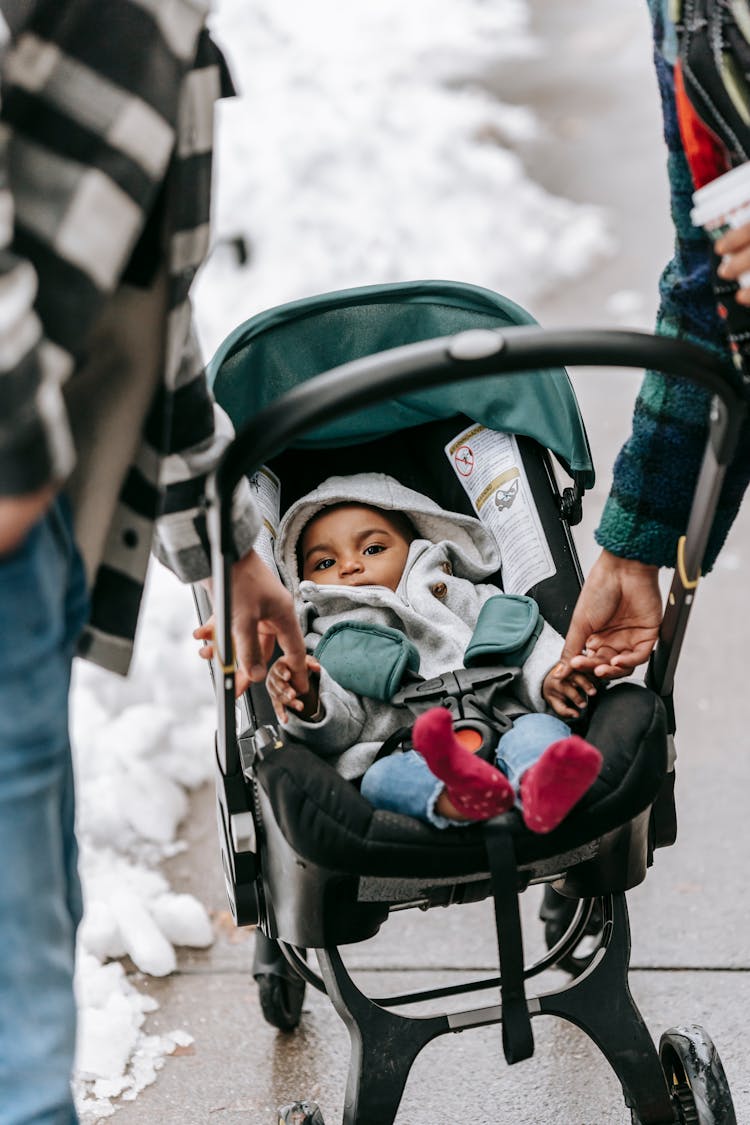 Ethnic Baby Lying In Stroller During Stroll With Parents