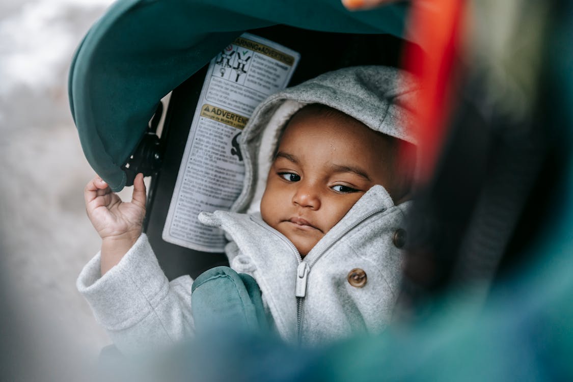 Free Little ethic baby in hood in stroller Stock Photo