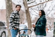 Smiling ethnic couple standing on roadside with baby in stroller