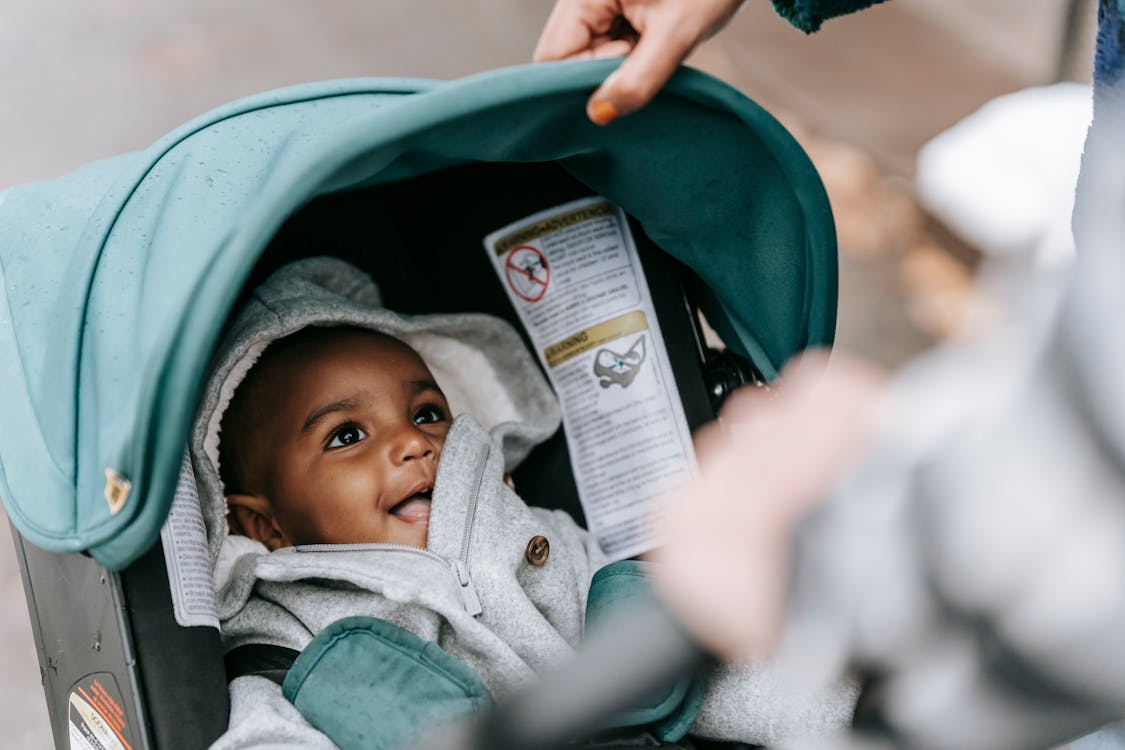 Free Smiling cute ethnic baby in stroller with parents Stock Photo