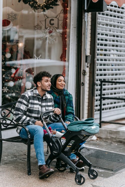 Free Ethnic couple sitting with baby in stroller at Christmas holidays Stock Photo