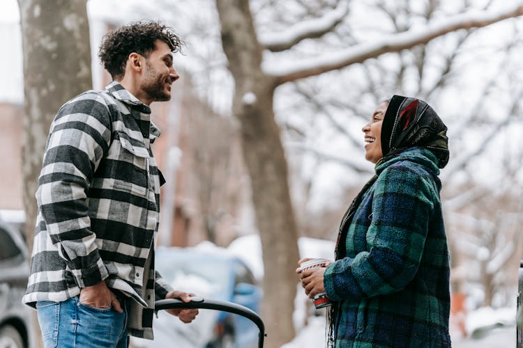 Smiling Ethnic Couple With Stroller On Sidewalk