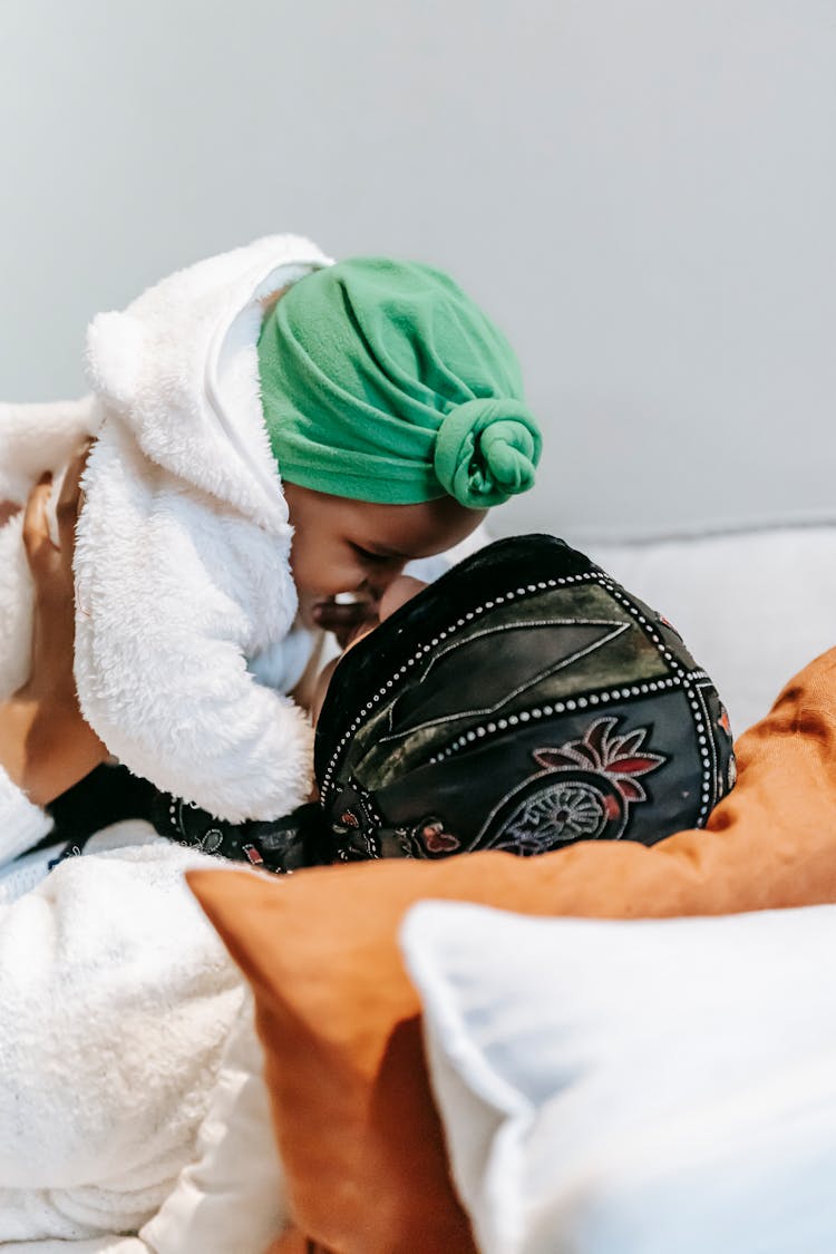 Anonymous Black Mother Playing With Baby Lying On Bed