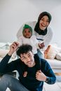 Cheerful young multiracial parent with curious baby smiling and looking at camera while having fun during weekend at home