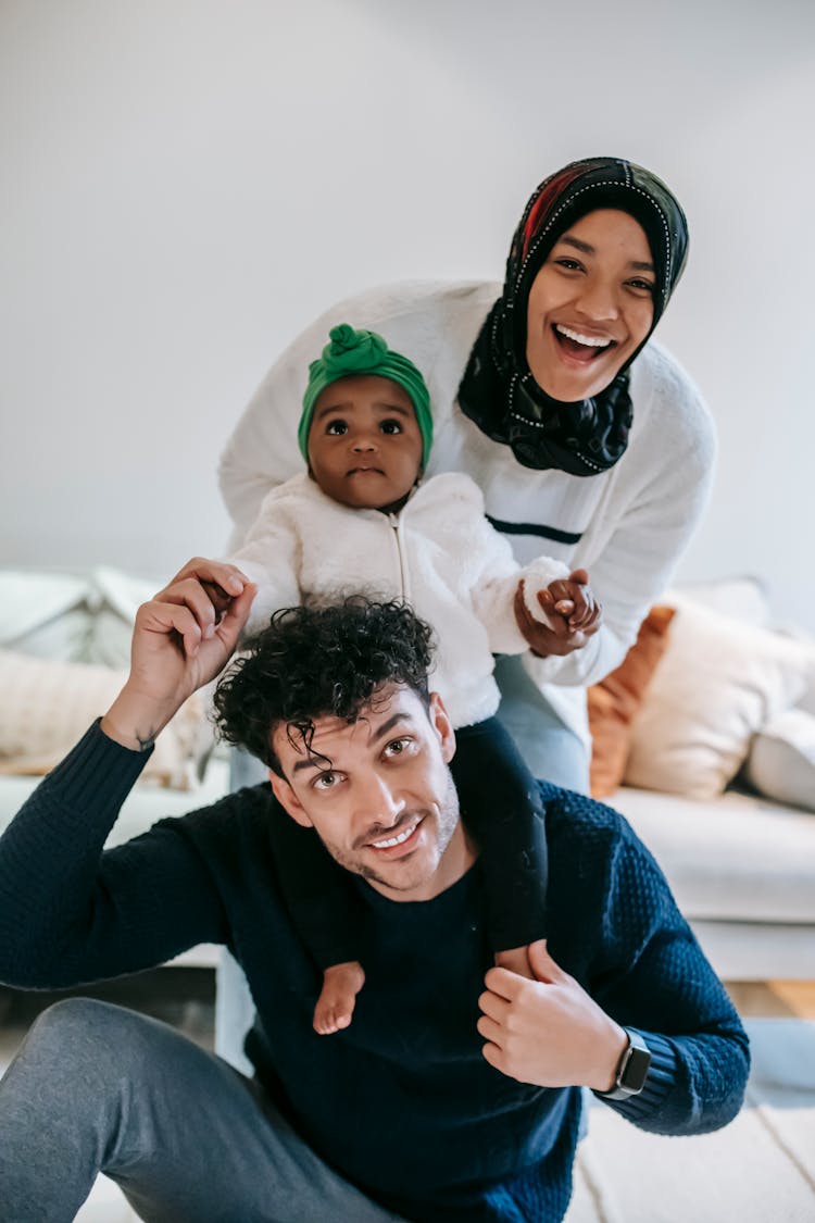 Delighted Young Diverse Parents Laughing And Playing With Baby At Home