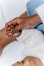 Anonymous ethnic woman touching hand of sleeping baby on bed