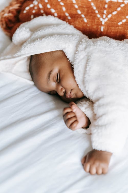 Free Adorable African American baby sleeping on comfy bed Stock Photo