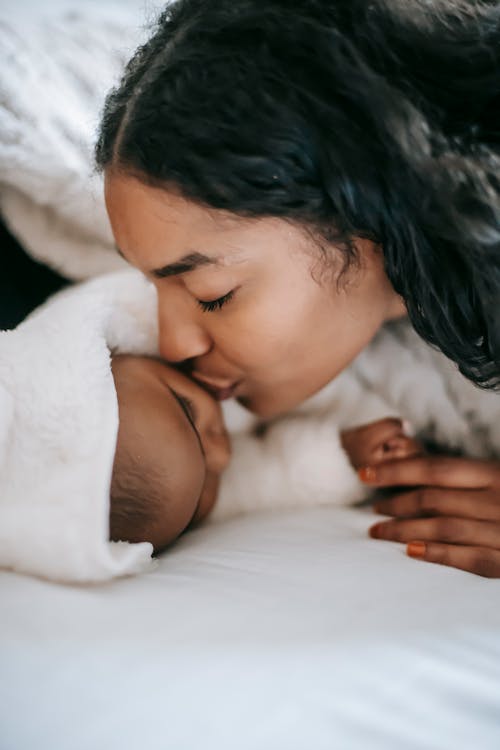 Foto De Close Up De Uma Mãe Beijando Seu Bebê Dormindo