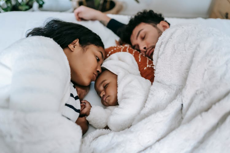 Calm Ethnic Family Sleeping On Bed In Bedroom