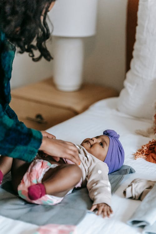 Crop black mother with baby on bed