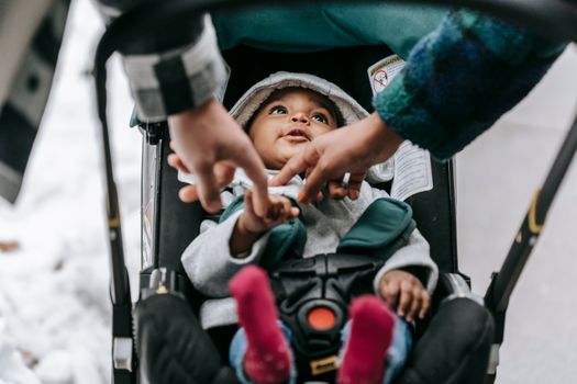 Crop parents with black baby in carriage