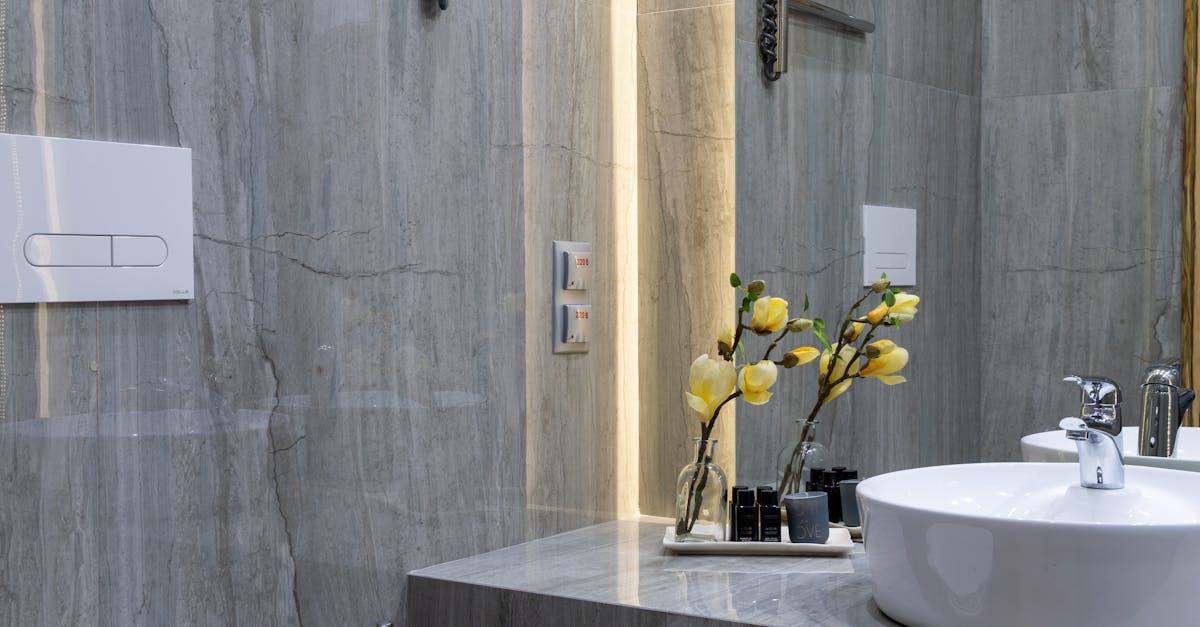 Interior of modern bathroom with sink placed at mirror on marble gray surface with flowers near white ceramic bidet at home