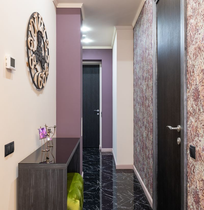 Narrow corridor with a wooden console cupboard and decorations in a small home
