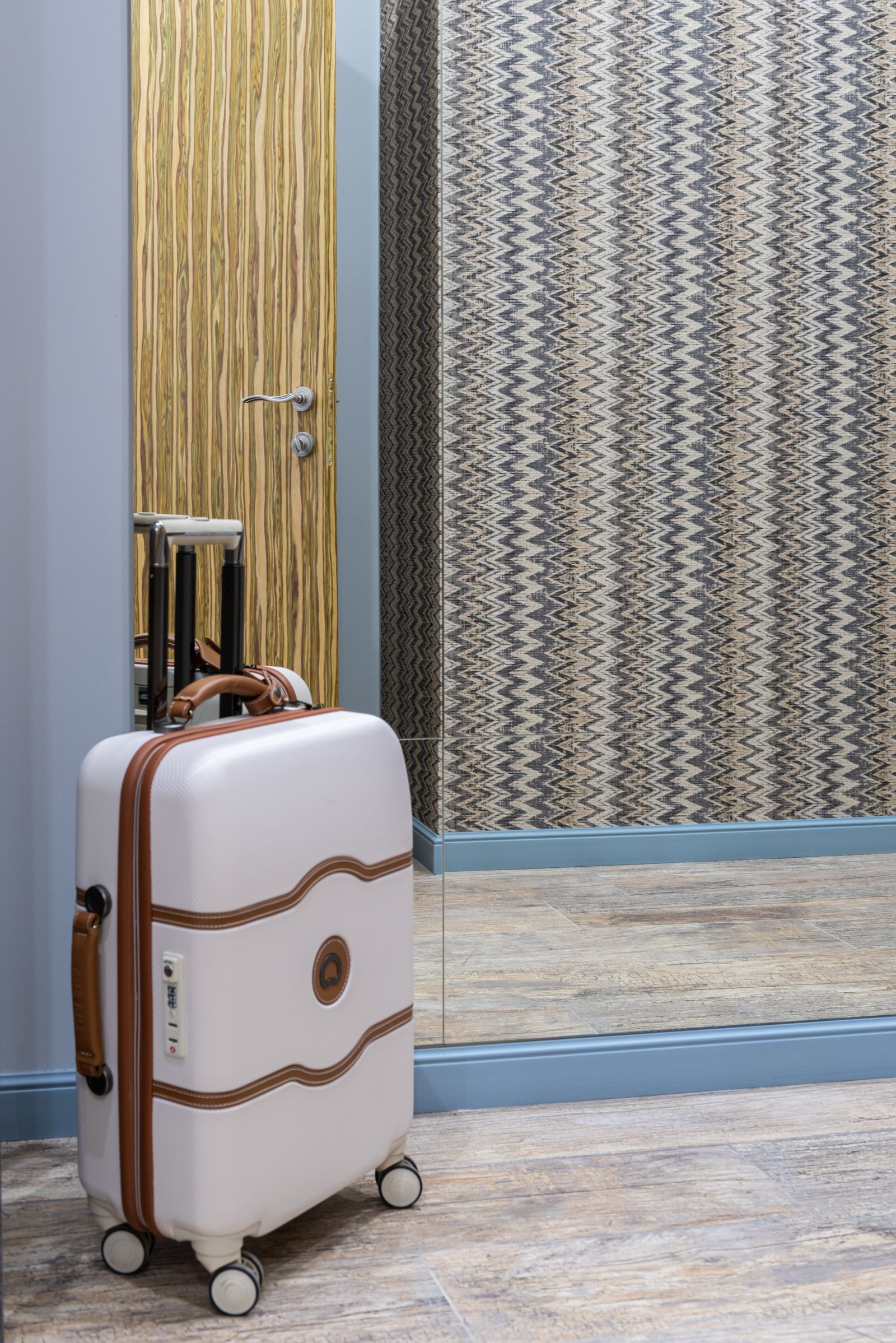 Suitcase beside a mirror in a modern hotel room