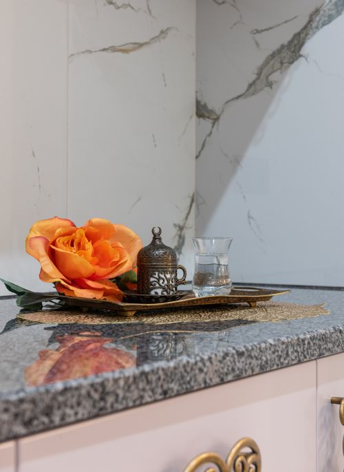 Free Traditional antique coffee cup and glass of water placed on marble surface of cupboard with orange rose near wall in room Stock Photo